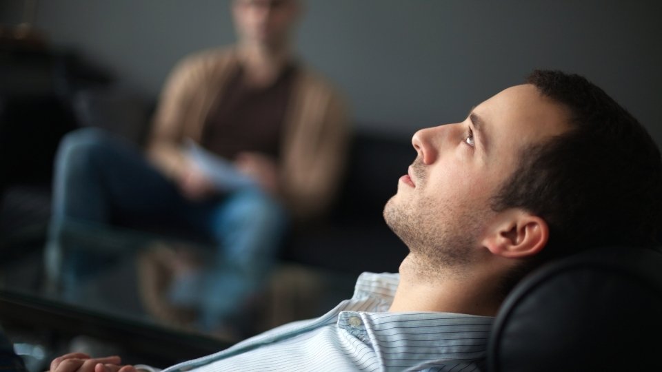 How Long Is Rehab for Alcohol? A man sits in therapy, wondering the answer to this question.