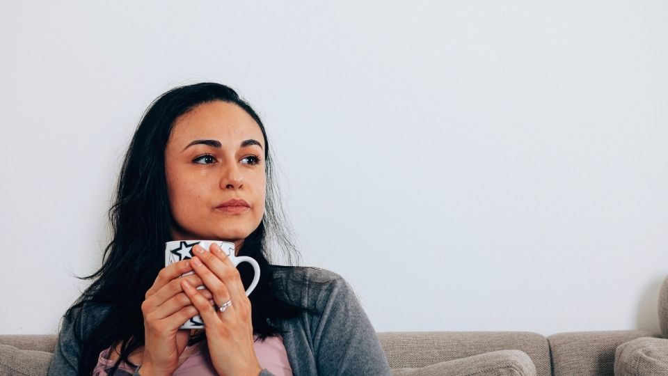a woman drinks from a mug during recovery after quitting alcohol.