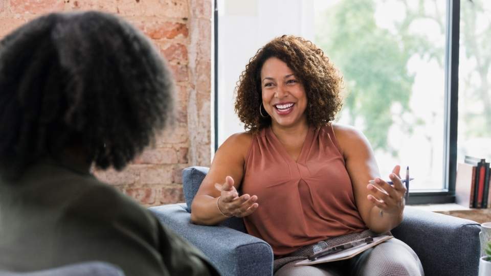 How Long Is a Partial Hospitalization Program hero image of a woman talking in therapy.